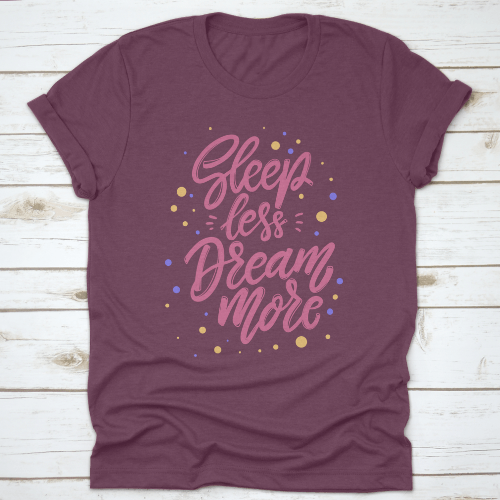 A stylish T-shirt featuring the phrase 'Sleep Less Dream More' in a cute lettering design, made from 100% cotton for comfort.