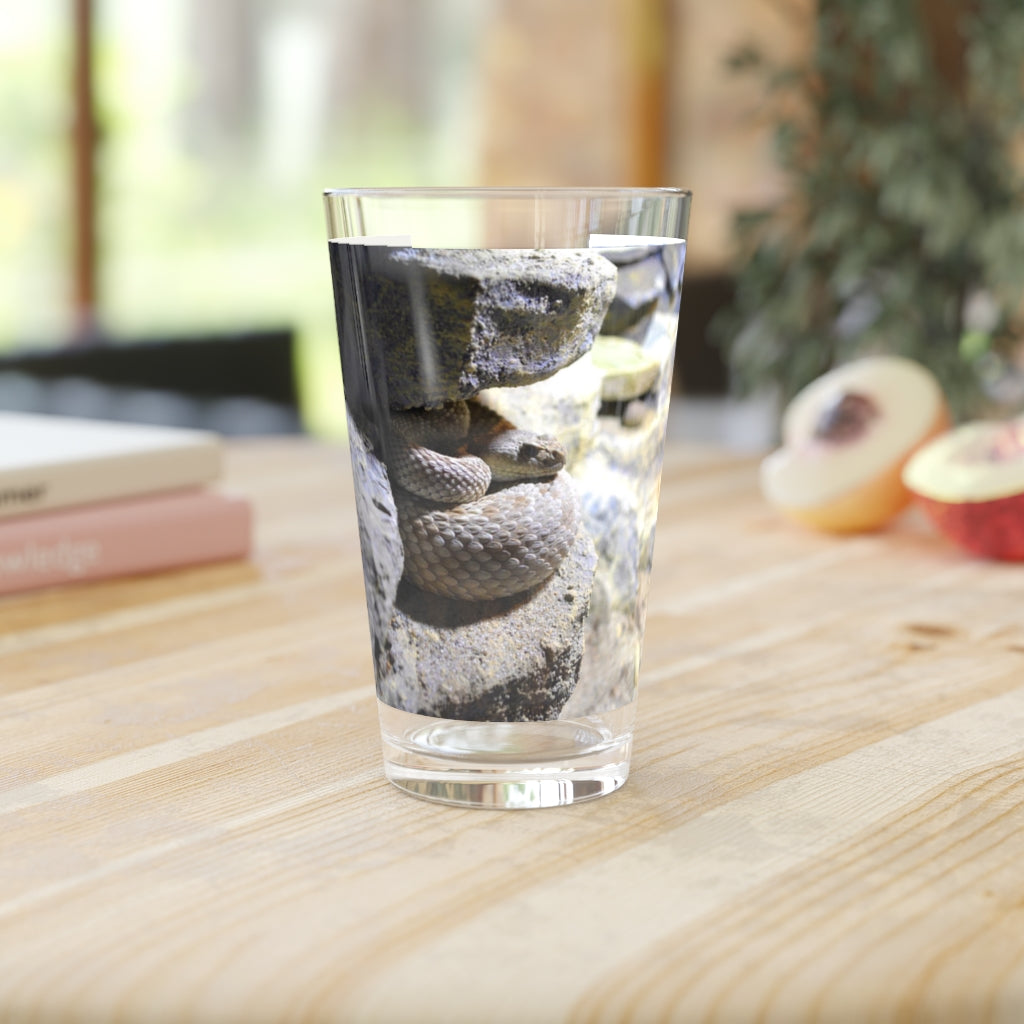 A clear 16oz Snake Pint Glass showcasing a custom printed design, perfect for beverages.