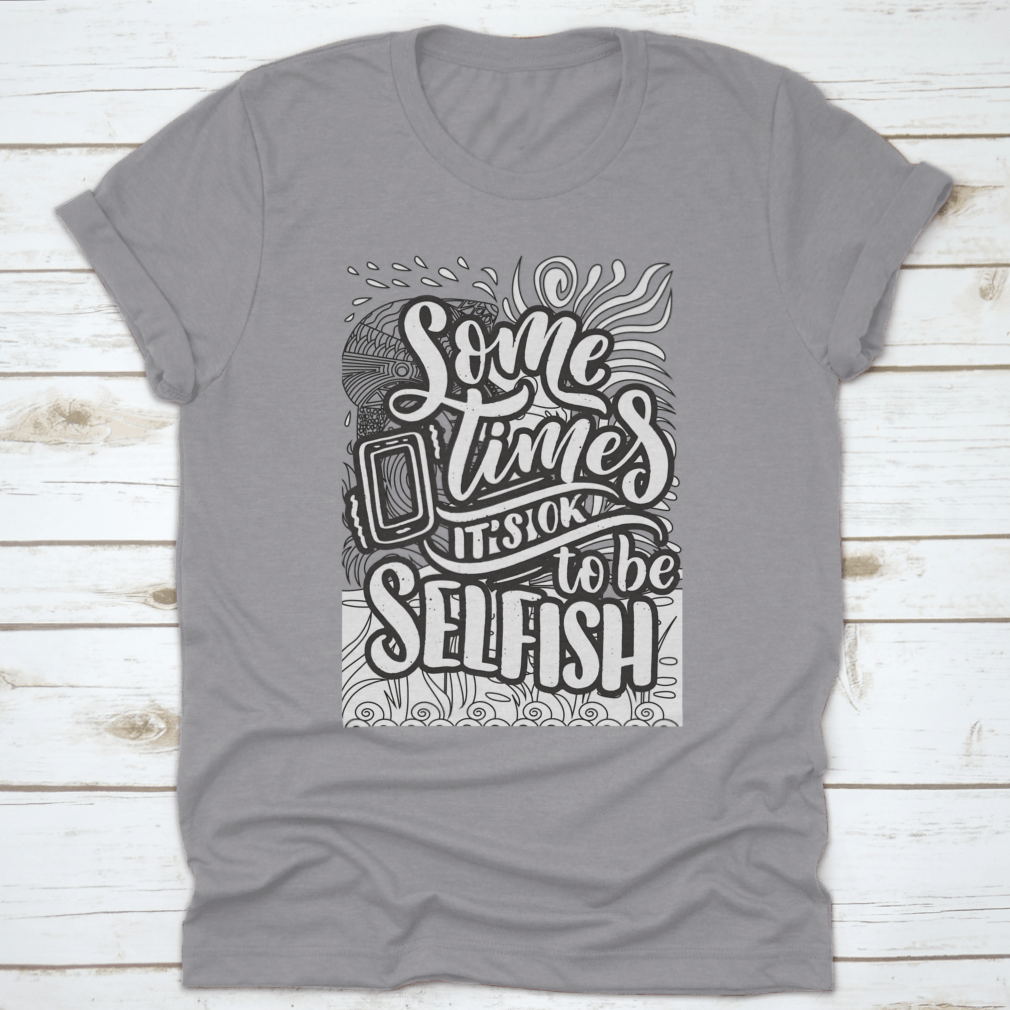 A stylish grey T-shirt featuring the inspirational quote 'Sometimes It's Okay To Be Selfish' in bold lettering, made from soft cotton fabric.