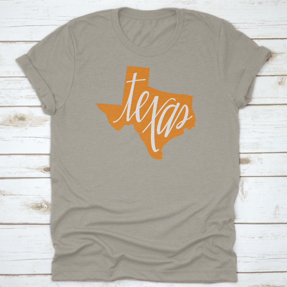 A stylish Texas State Outline and Hand Lettering Shirt, showcasing a unique design on a comfortable cotton fabric.