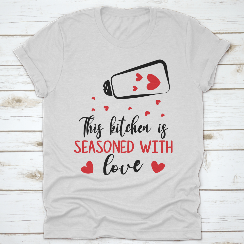 A stylish t-shirt featuring the quote 'This Kitchen Is Seasoned With Love', made from soft cotton fabric, perfect for cooking enthusiasts.