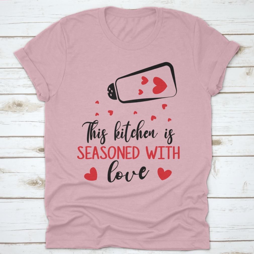 A stylish t-shirt featuring the quote 'This Kitchen Is Seasoned With Love', made from soft cotton fabric, perfect for cooking enthusiasts.