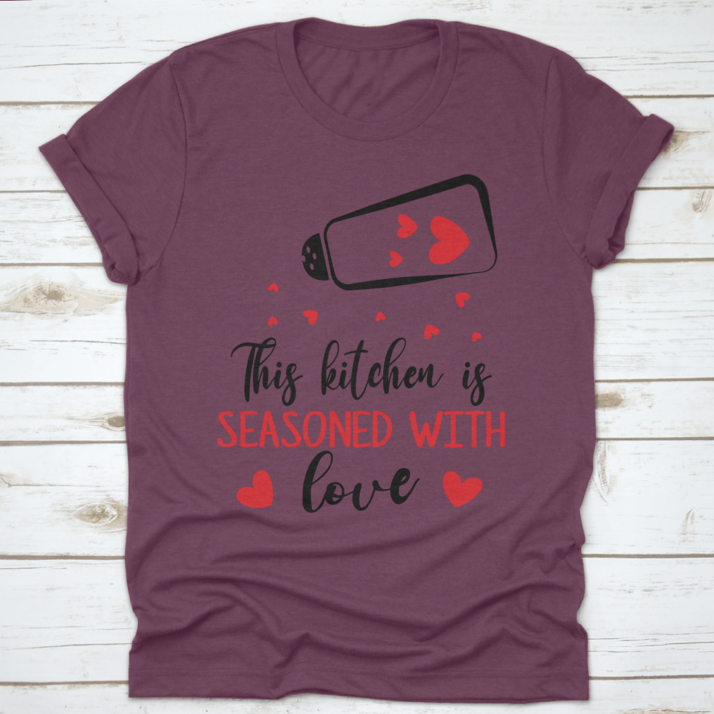 A stylish t-shirt featuring the quote 'This Kitchen Is Seasoned With Love', made from soft cotton fabric, perfect for cooking enthusiasts.