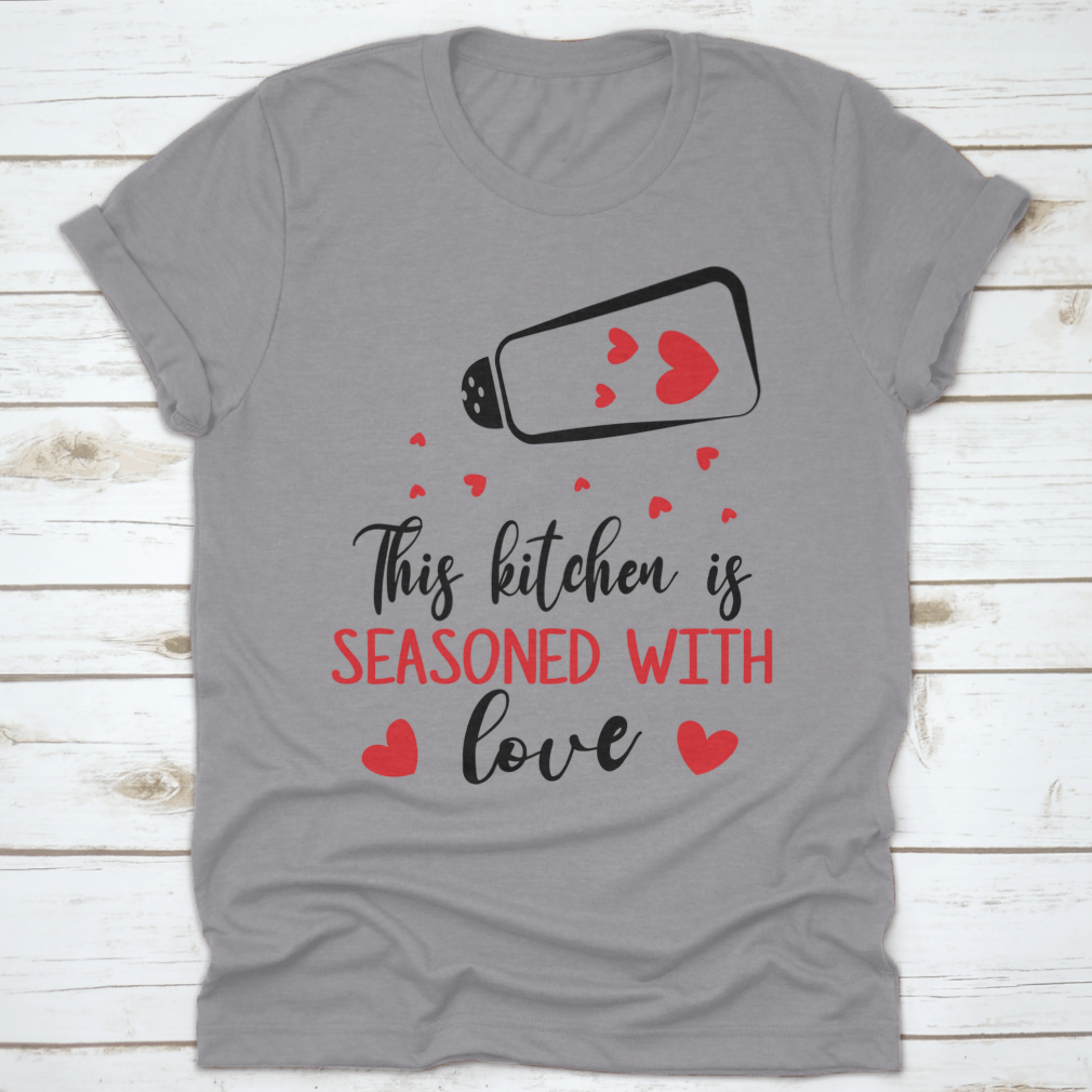 A stylish t-shirt featuring the quote 'This Kitchen Is Seasoned With Love', made from soft cotton fabric, perfect for cooking enthusiasts.