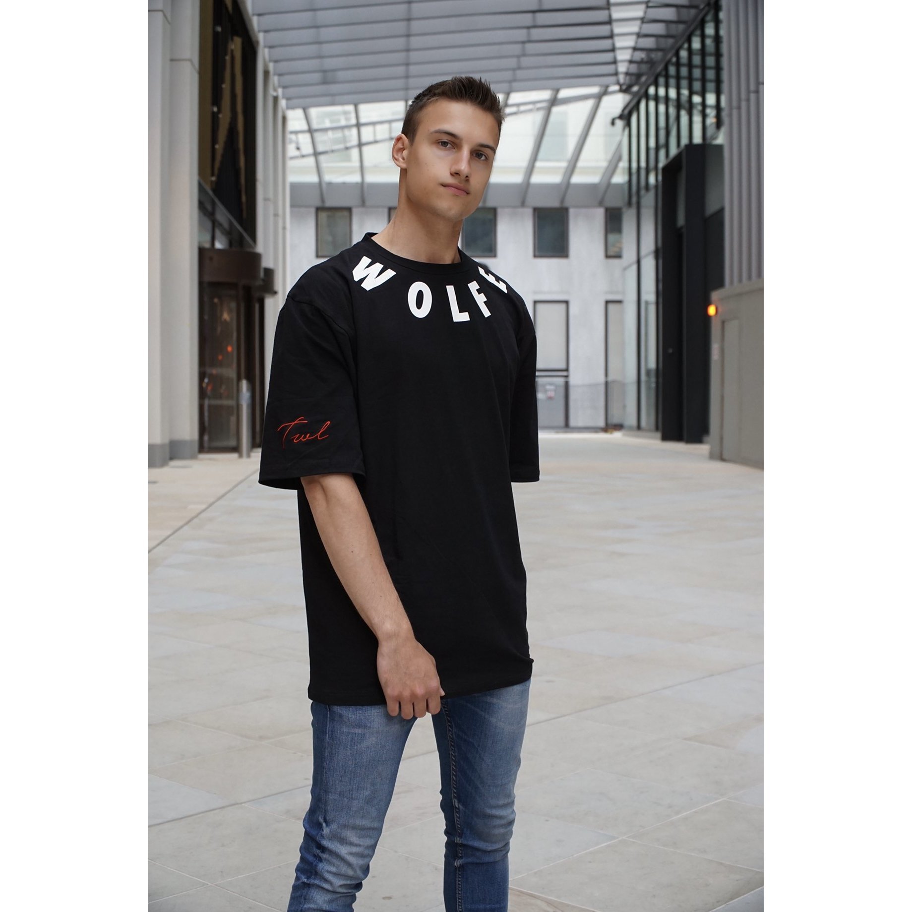 Wolfe Orbit T-shirt featuring oversized fit, white 'WOLFE' text around the neck, and red 'TWL' signature on the arm.