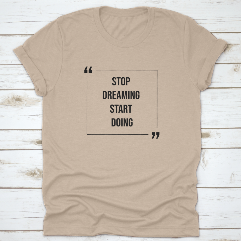 A motivational Word Shirt featuring the phrase 'Stop Dreaming Start', made from soft cotton fabric, displayed on a neutral background.