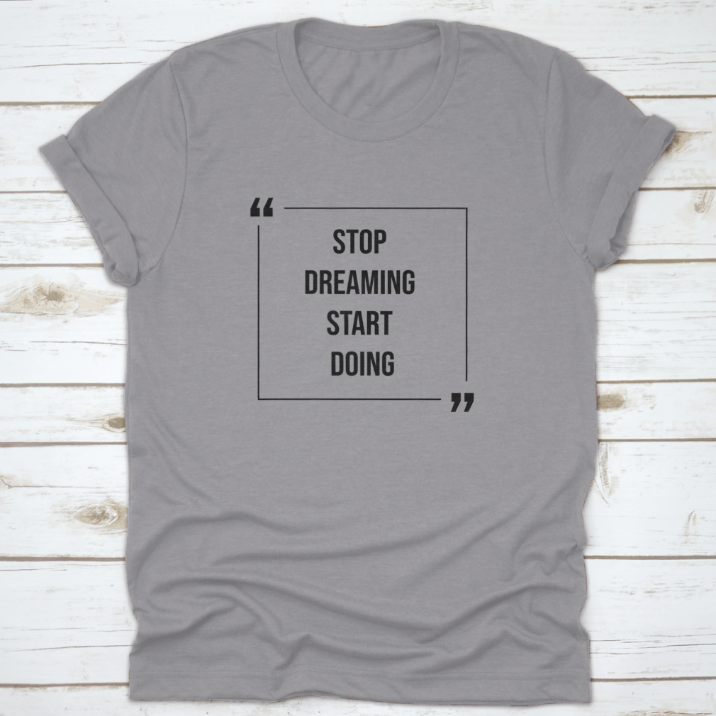 A motivational Word Shirt featuring the phrase 'Stop Dreaming Start', made from soft cotton fabric, displayed on a neutral background.