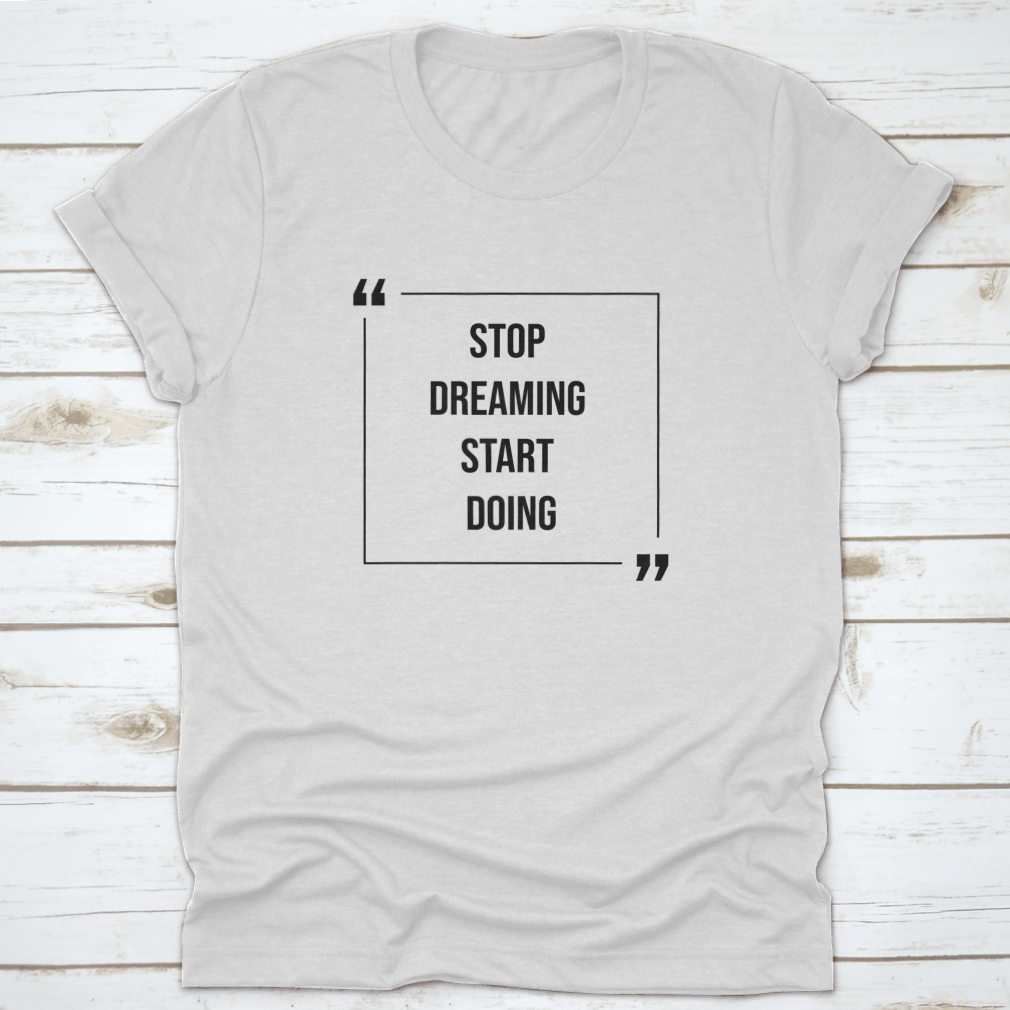 A motivational Word Shirt featuring the phrase 'Stop Dreaming Start', made from soft cotton fabric, displayed on a neutral background.