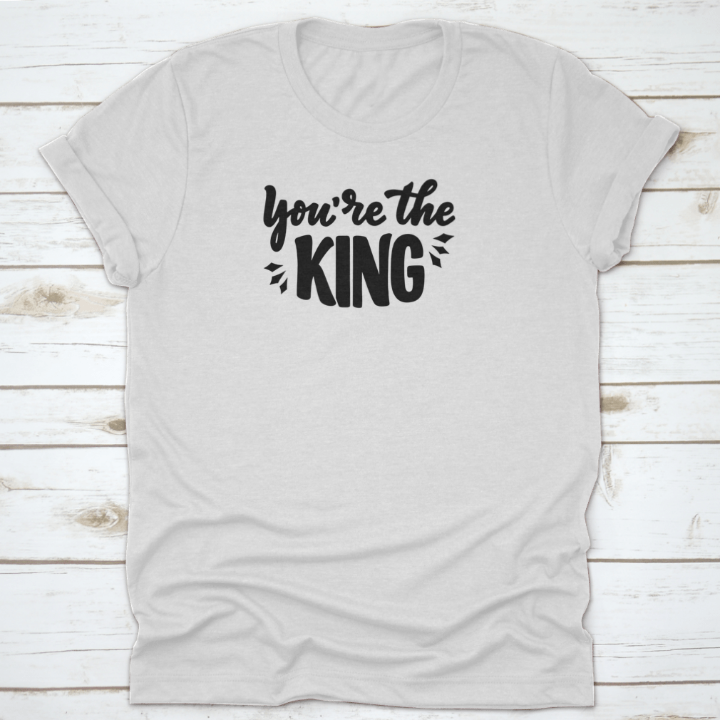 A stylish T-shirt featuring the hand-drawn phrase 'You're The King' in modern lettering, made from soft cotton fabric.