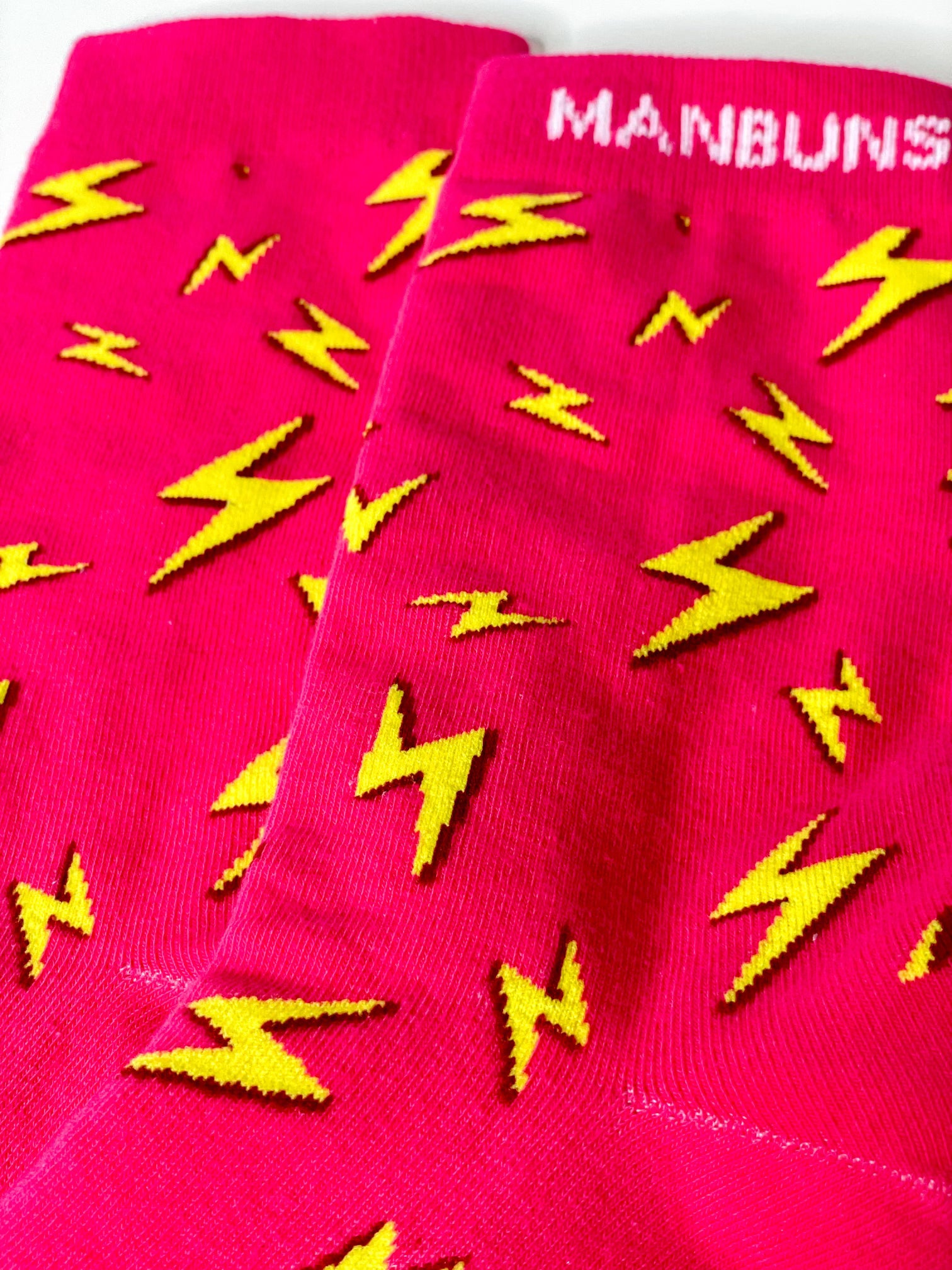 A pair of vibrant pink crew socks featuring a bold lightning bolt design, perfect for adding a fun touch to any outfit.