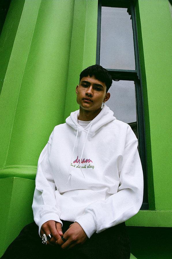 A white hoodie featuring a colorful 90s logo design with the text 'Dream But Do Not Sleep' printed on the front chest.