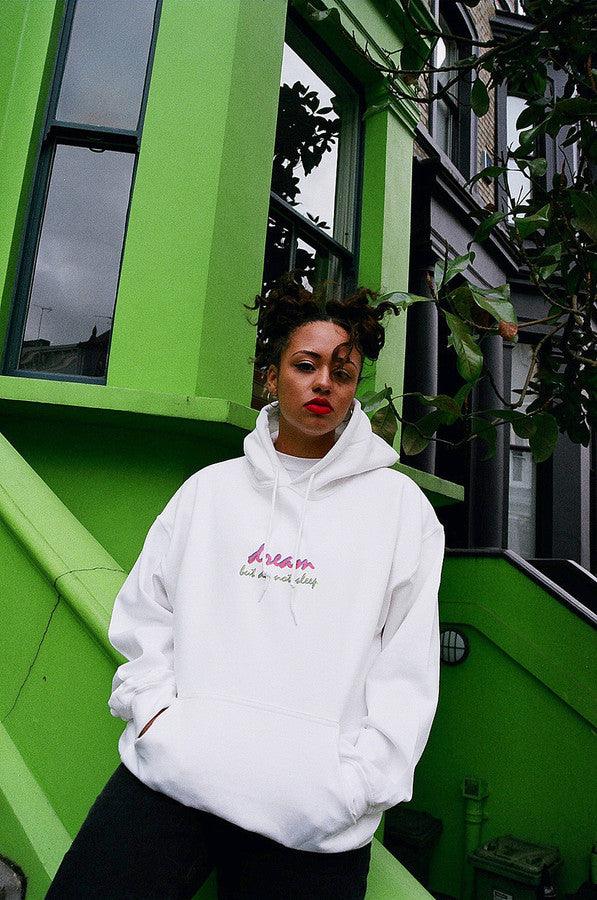 A white hoodie featuring a colorful 90s logo design with the text 'Dream But Do Not Sleep' printed on the front chest.