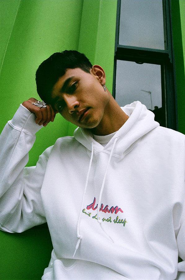 A white hoodie featuring a colorful 90s logo design with the text 'Dream But Do Not Sleep' printed on the front chest.