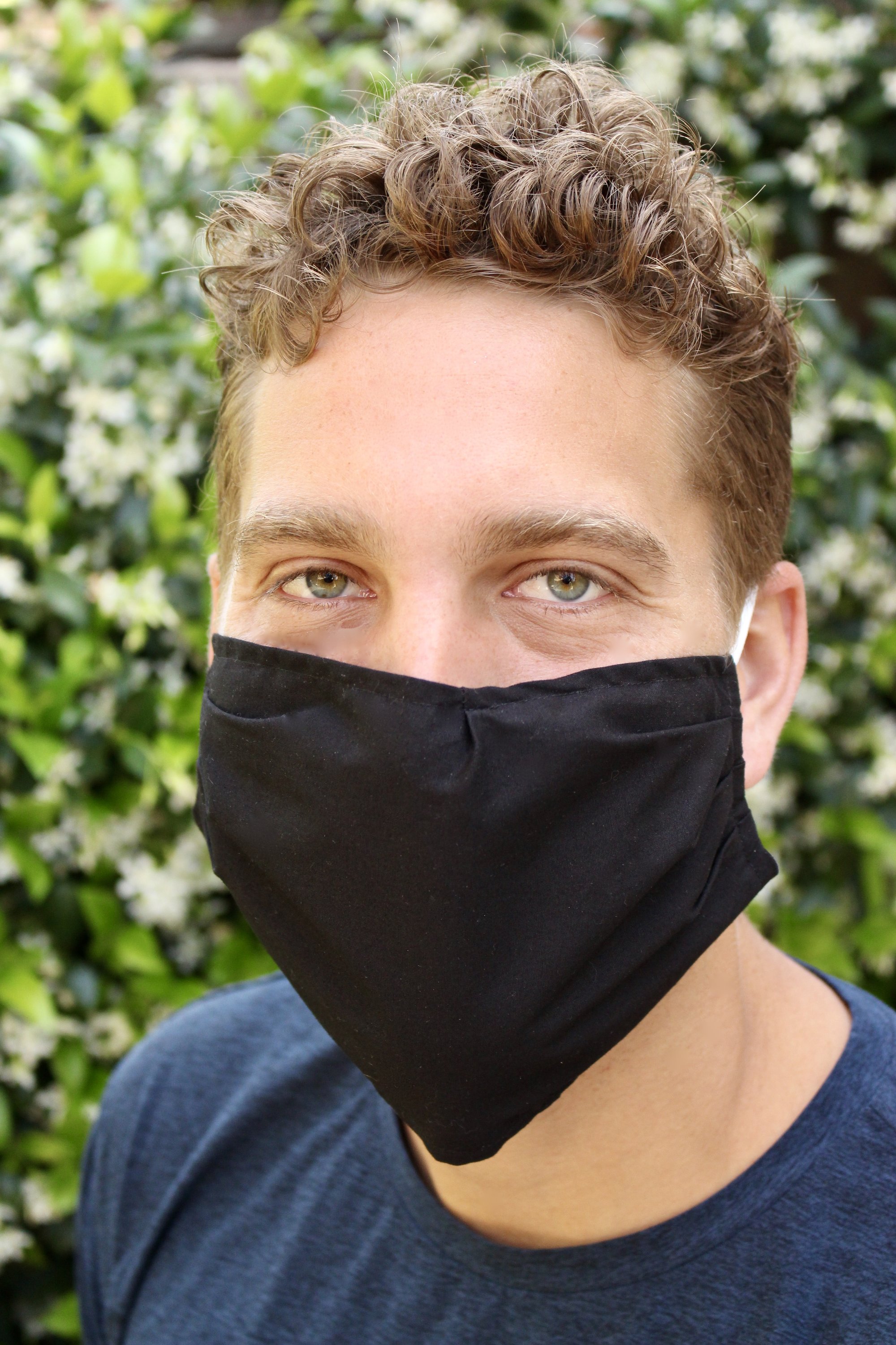 Black large face mask made of breathable cotton with pleats for comfort and a pocket for filters, suitable for everyday use.