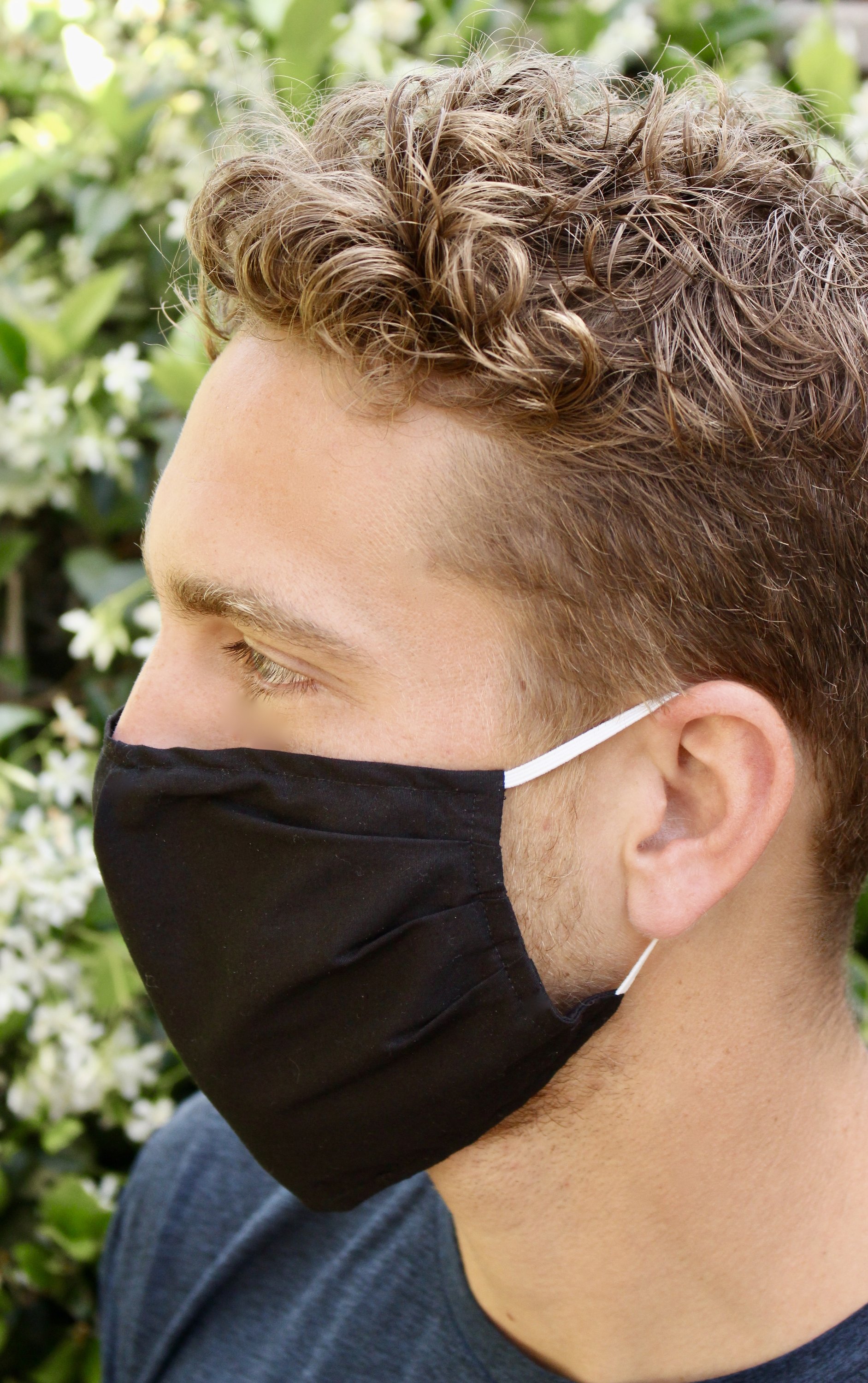 Black large face mask made of breathable cotton with pleats for comfort and a pocket for filters, suitable for everyday use.