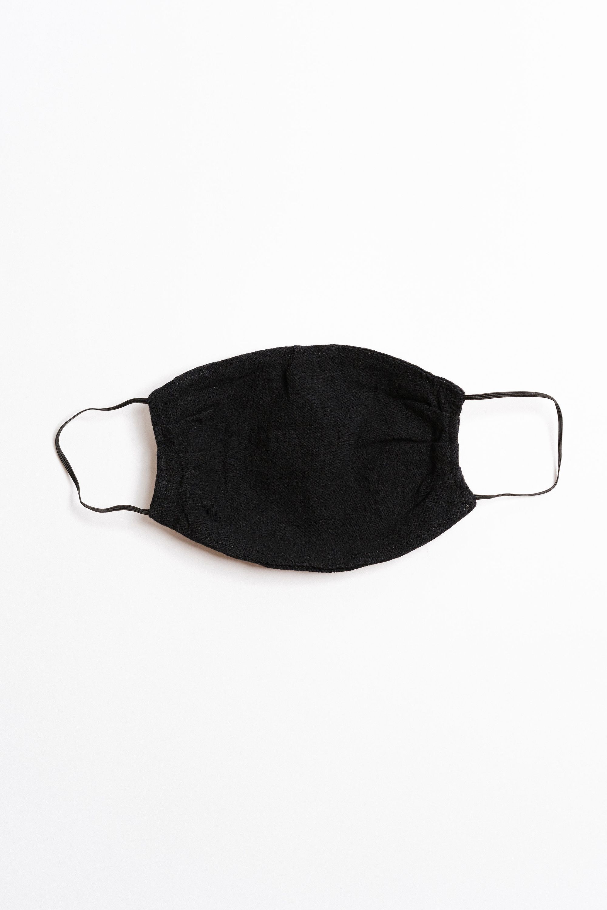 Black textured face mask with black elastic ear straps, designed for comfort and safety, featuring a pocket for filter insertion.