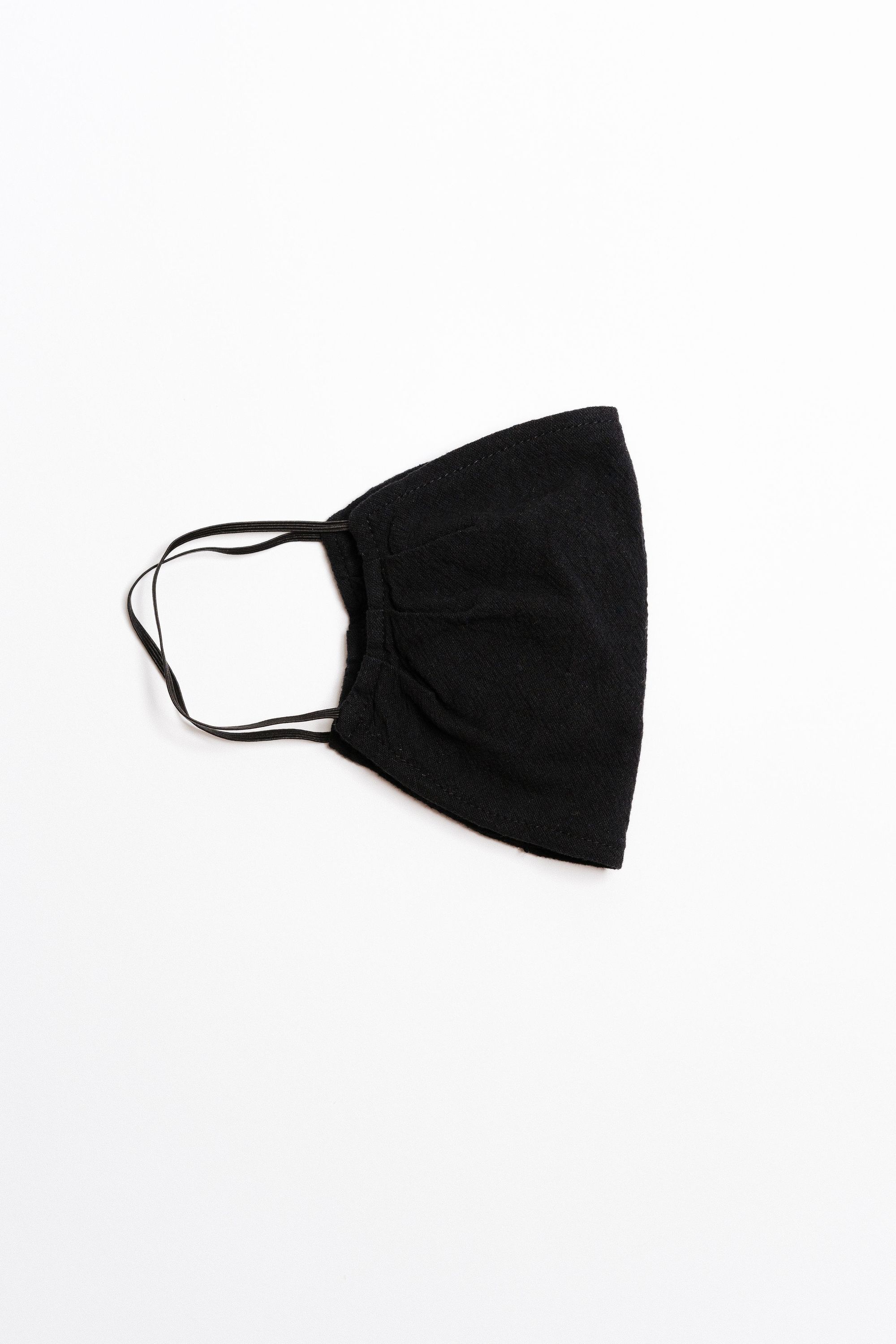 Black textured face mask with black elastic ear straps, designed for comfort and safety, featuring a pocket for filter insertion.