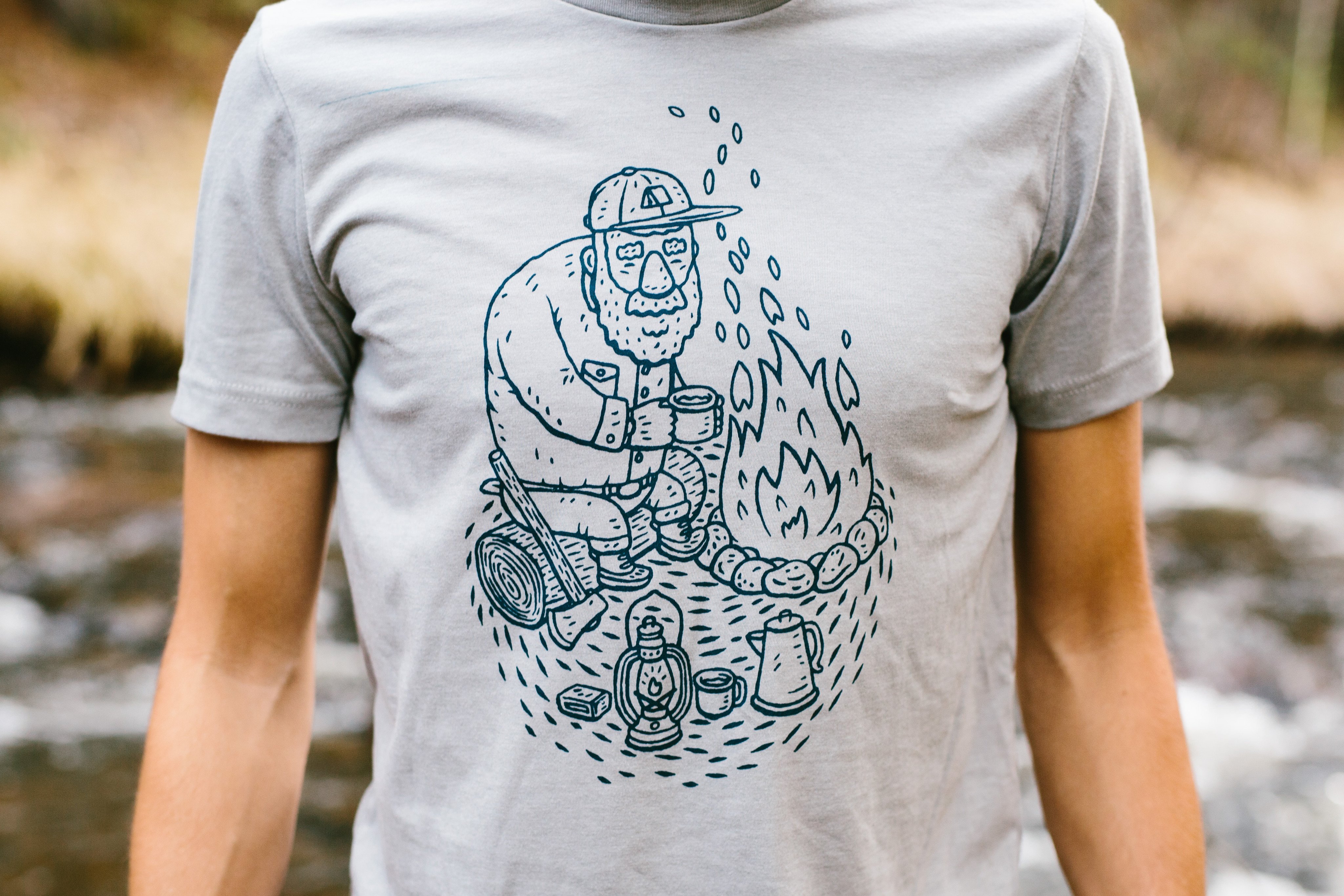 Gray Campfire Tee featuring a navy screen printed design inspired by camping memories, made from soft ringspun cotton.