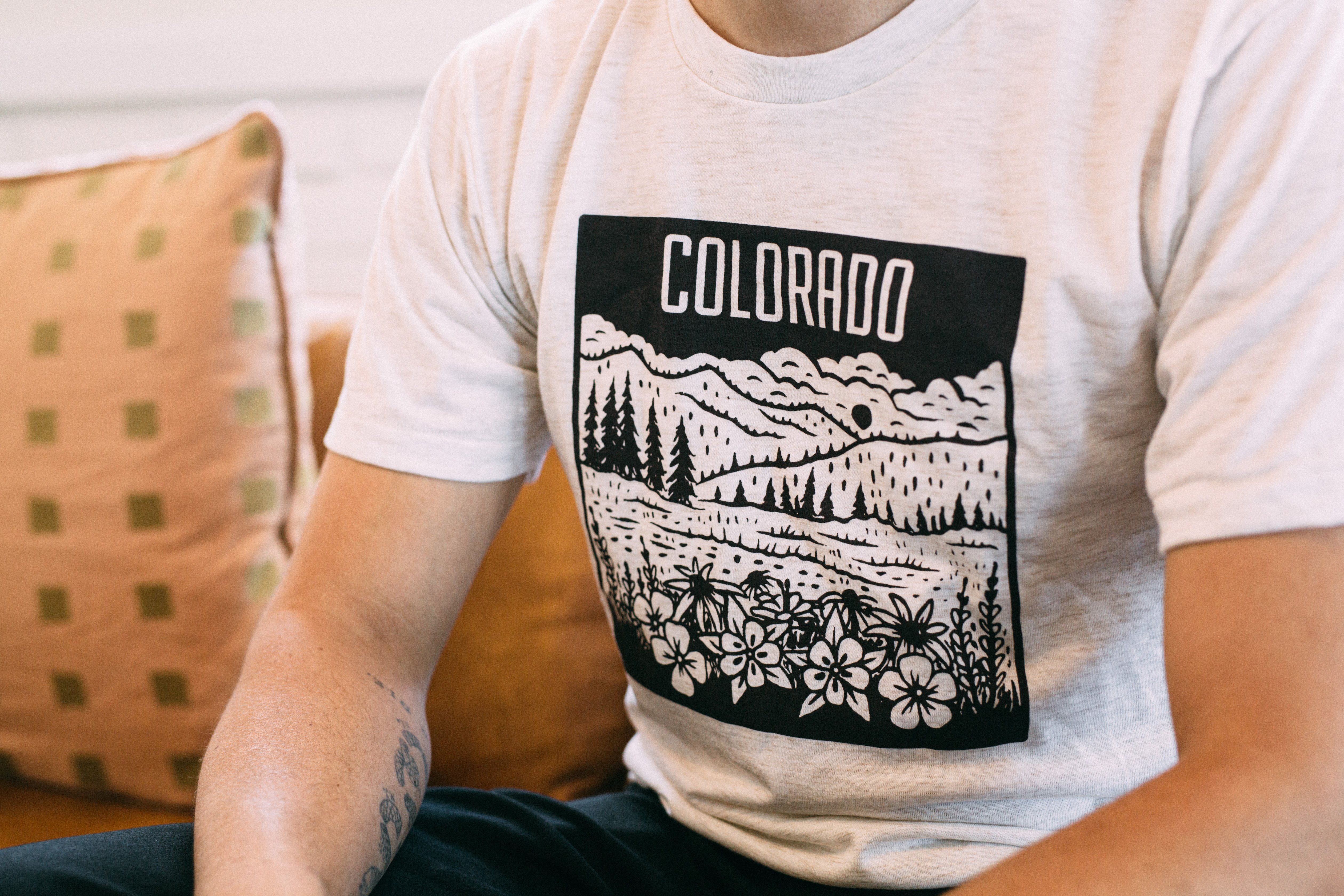 Colorado Mountain Tee in oatmeal color featuring maroon screen print of Rocky Mountain design with wildflowers.