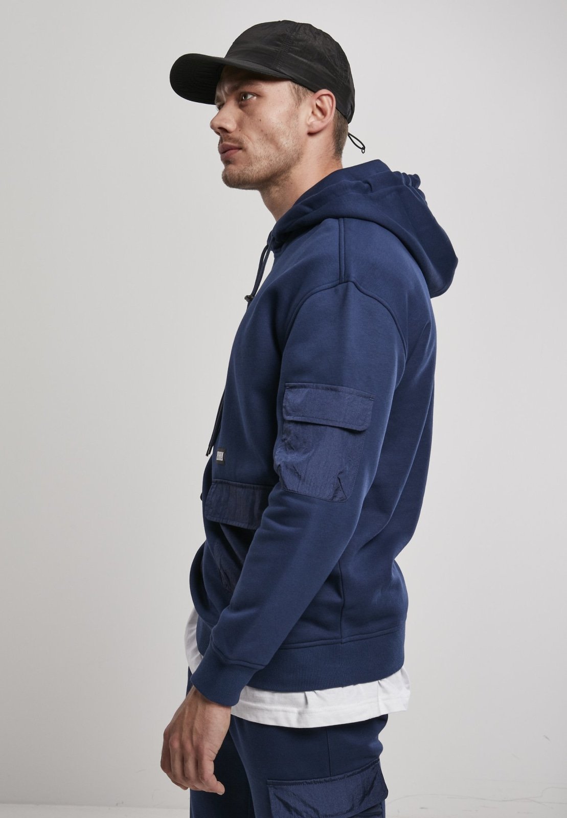 Men's Commuter Hoodie featuring three flap pockets, Urban Classics logo, and ribbed cuffs in soft Terry fabric.