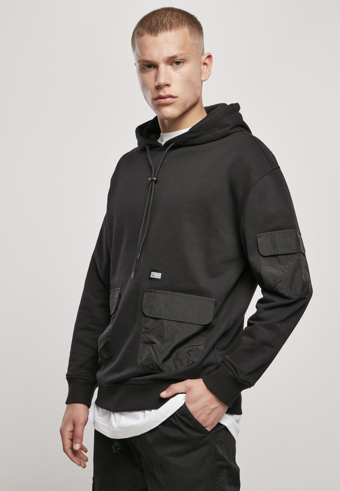 Men's Commuter Hoodie featuring three flap pockets, Urban Classics logo, and ribbed cuffs in soft Terry fabric.