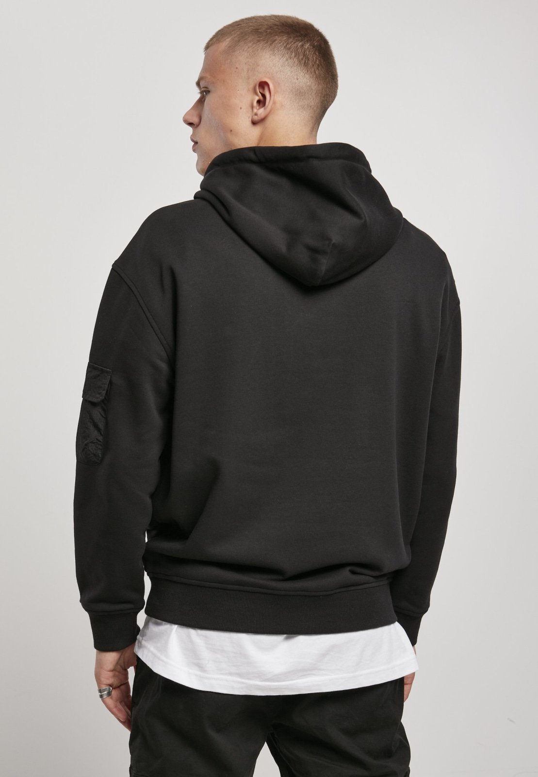 Men's Commuter Hoodie featuring three flap pockets, Urban Classics logo, and ribbed cuffs in soft Terry fabric.