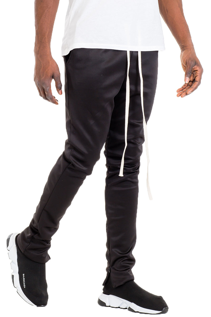 Essentials Track Pant in solid color with elastic waist and hidden ankle zipper, showcasing a modern skinny fit.