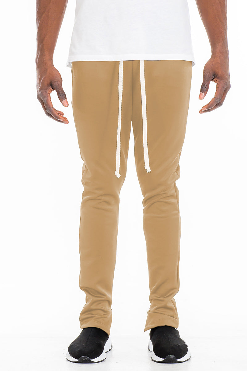 Essentials Track Pant in solid color with elastic waist and hidden ankle zipper, showcasing a modern skinny fit.