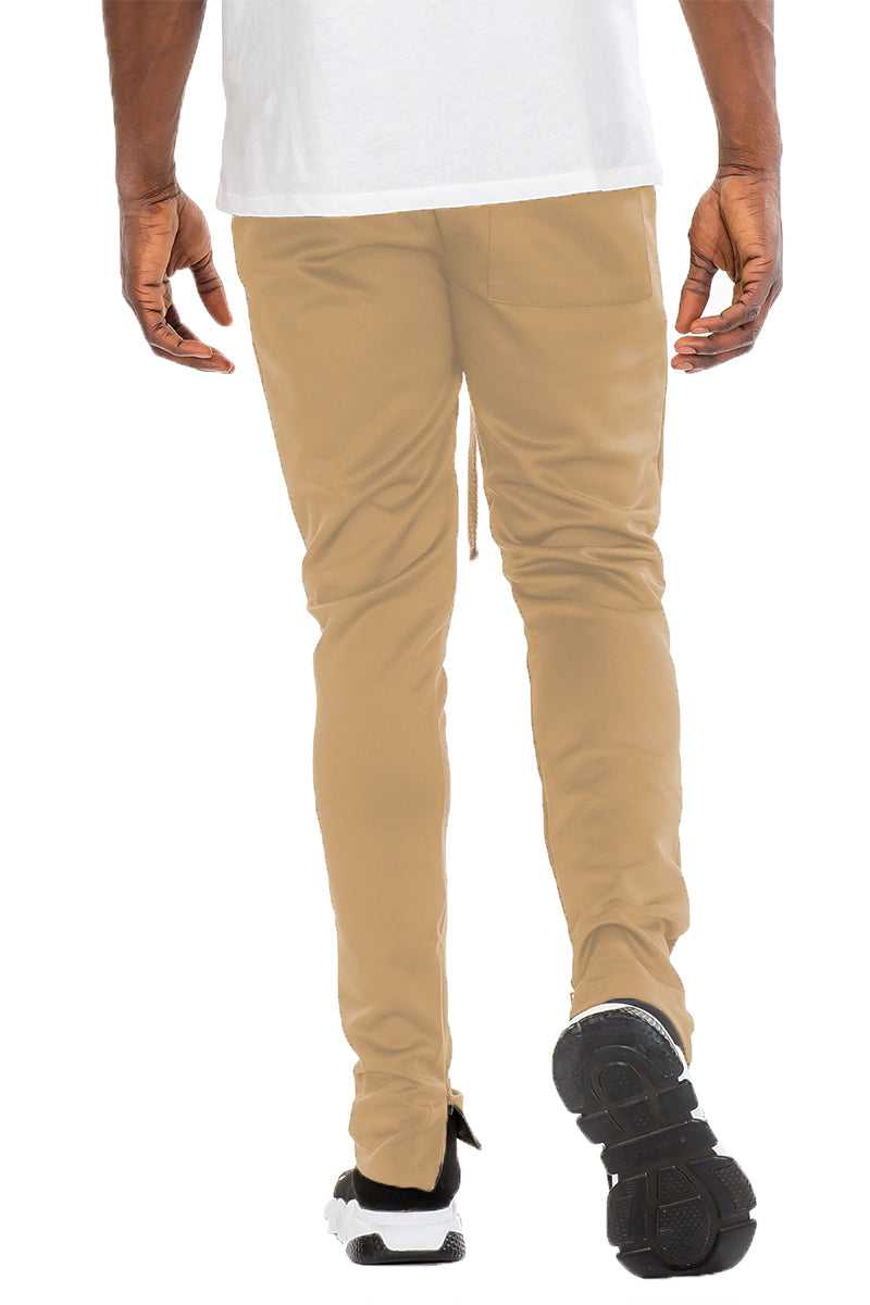 Essentials Track Pant in solid color with elastic waist and hidden ankle zipper, showcasing a modern skinny fit.