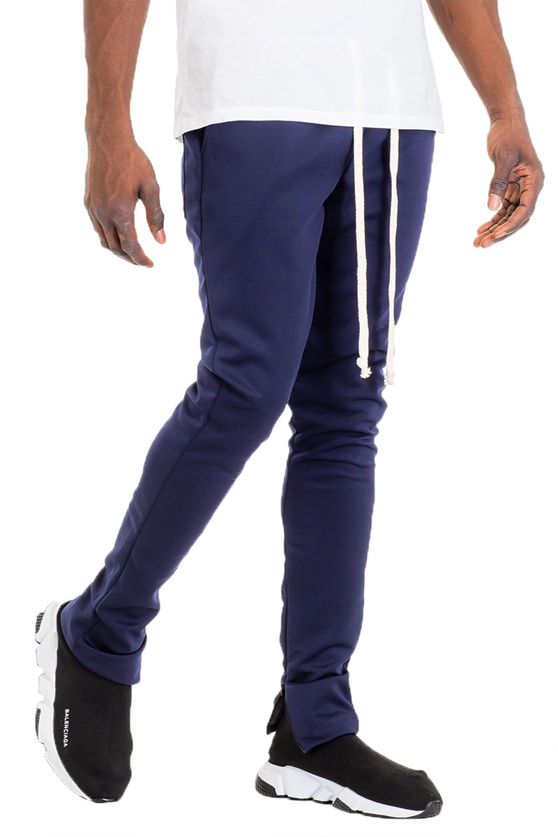 Essentials Track Pant in solid color with elastic waist and hidden ankle zipper, showcasing a modern skinny fit.