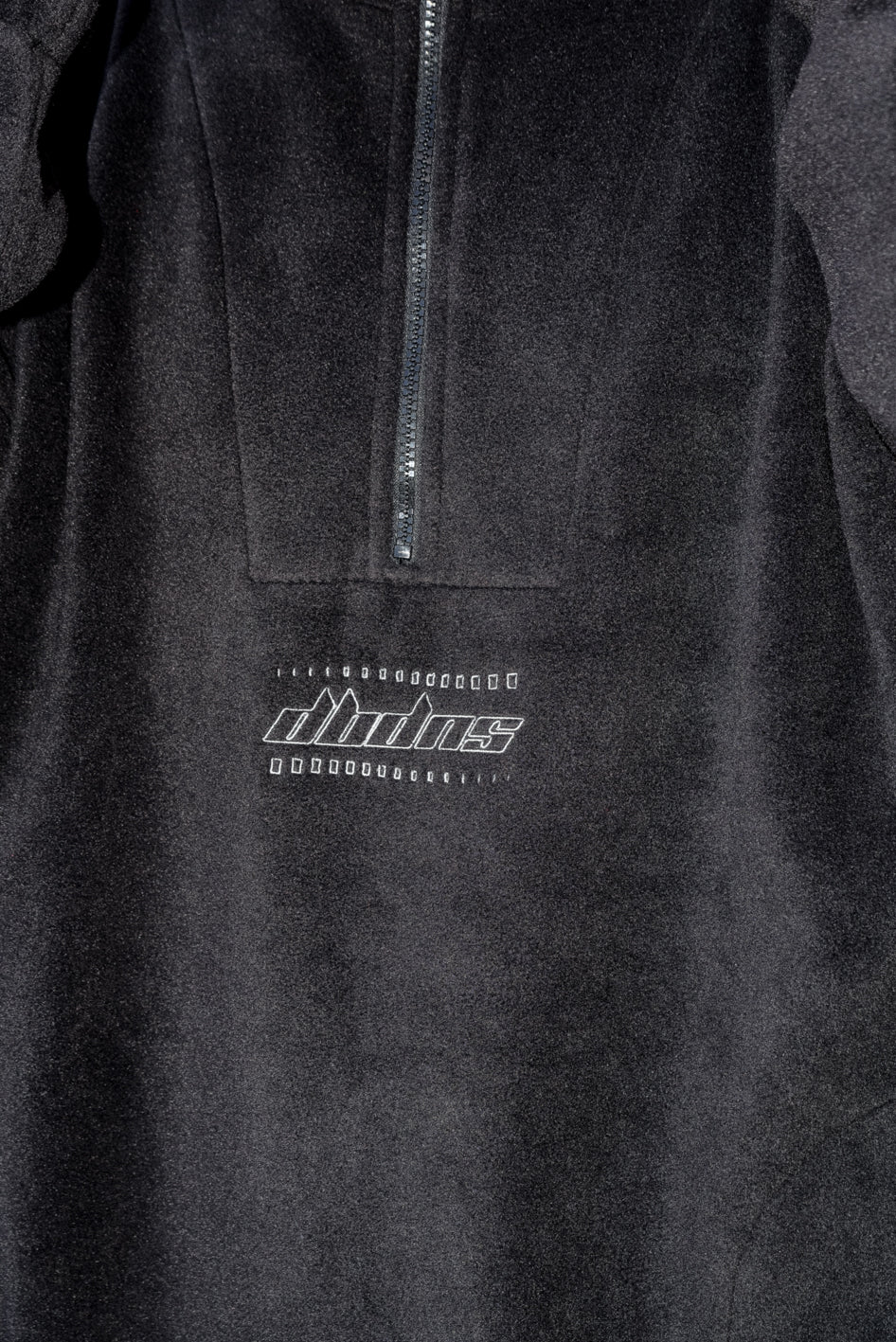 Black fleece with DBDNS Futuristic Logo Embroidery, featuring a 1/4 zip and two front pockets, showcasing a relaxed fit.