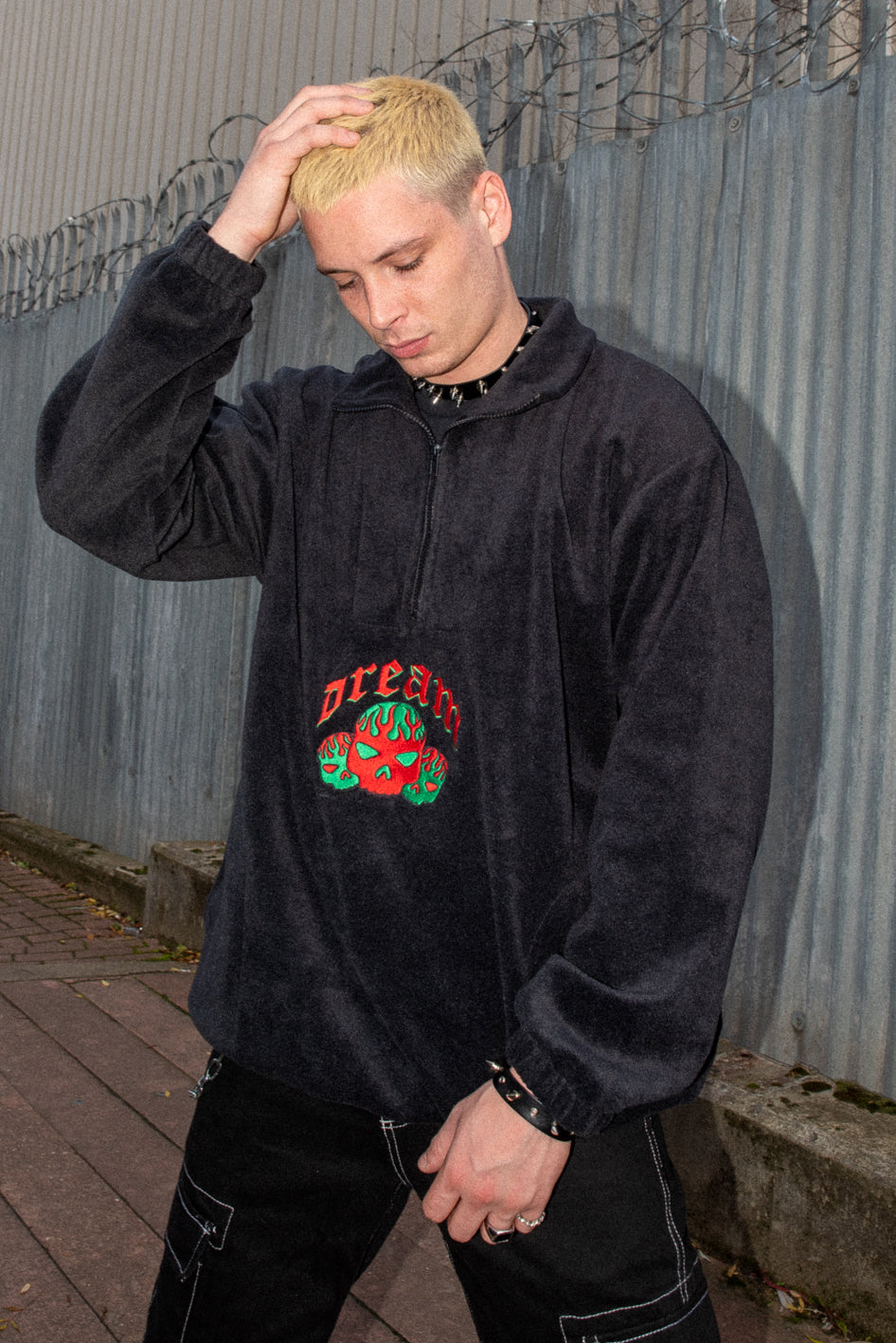 Black fleece jacket with flaming skull embroidery, featuring a 1/4 zip and two front pockets.