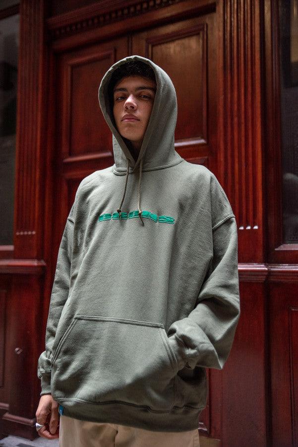 A stylish green hoodie featuring DBDNS embroidery logo on the front, showcasing a relaxed fit and label detailing on the hem.