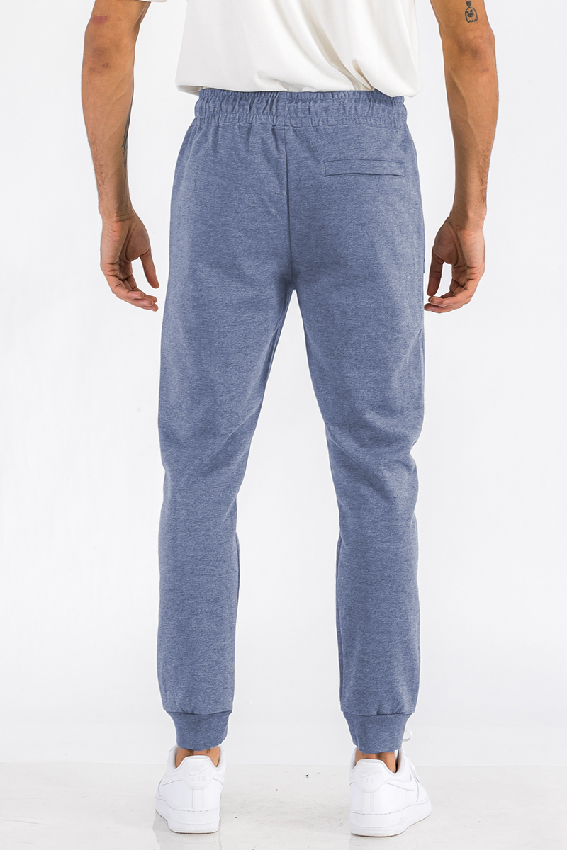 Heathered cotton sweats featuring an elastic waist, ankle cuffs, and a zipper pocket, displayed on a model.