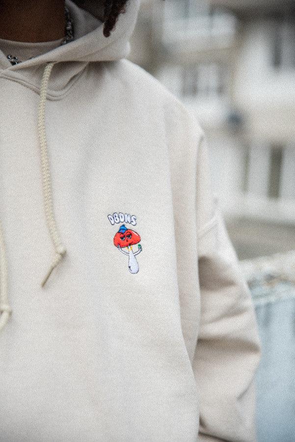 Bro Shroom hoodie in sand color featuring unique embroidery, relaxed fit, and woven label details.