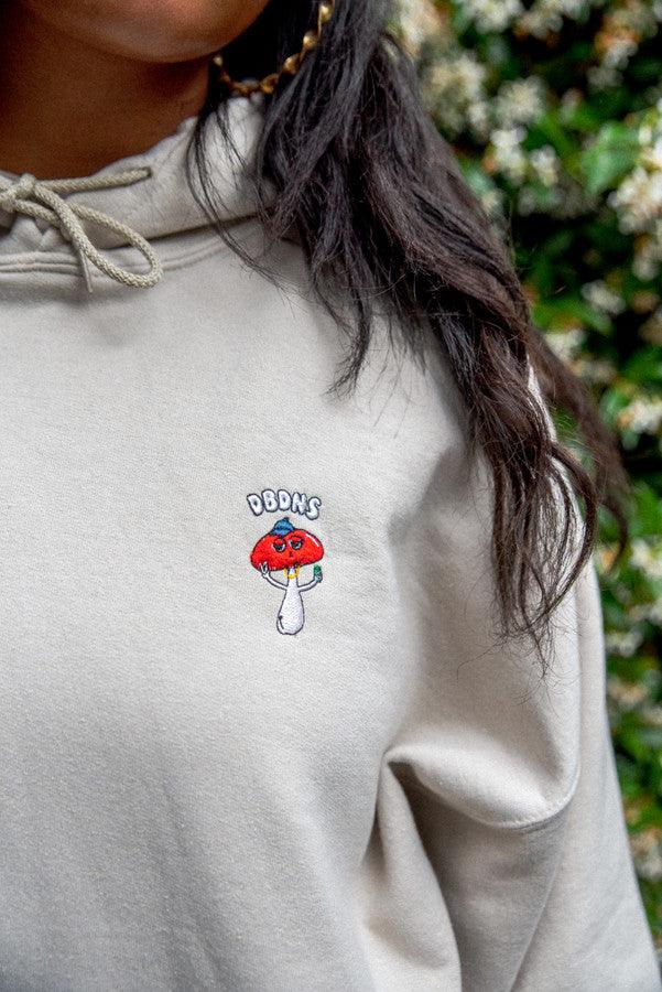 Bro Shroom hoodie in sand color featuring unique embroidery, relaxed fit, and woven label details.