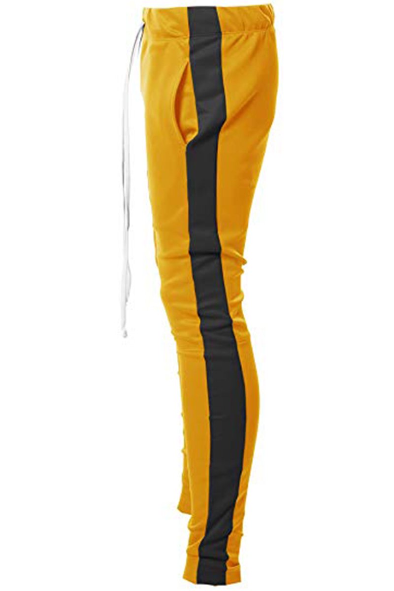 A pair of yellow and black Holiday track pants featuring a bold side stripe, adjustable elastic waistband, and sewn-in ankle zippers.