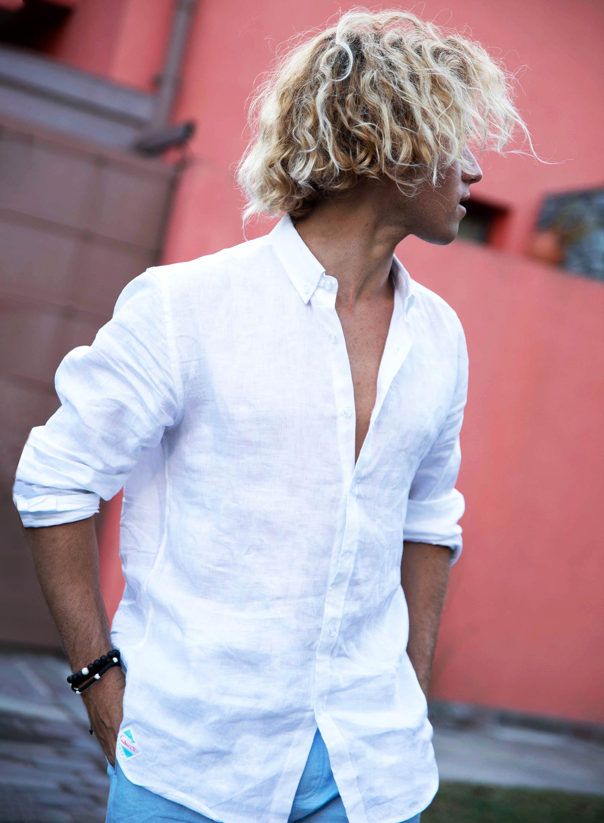 A stylish white linen shirt with a button-down collar, perfect for summer wear, displayed on a wooden hanger against a light background.