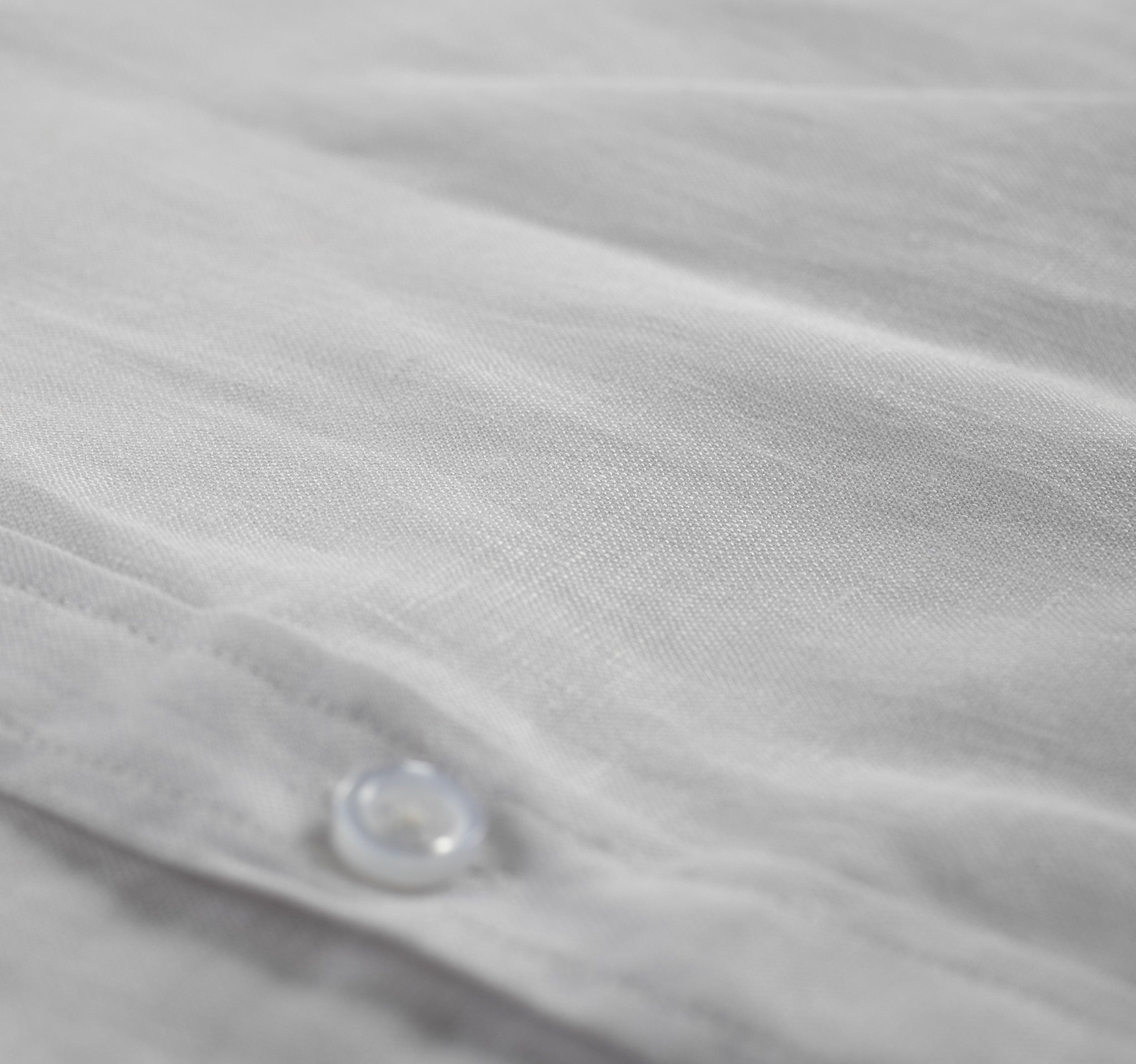 A stylish white linen shirt with a button-down collar, perfect for summer wear, displayed on a wooden hanger against a light background.