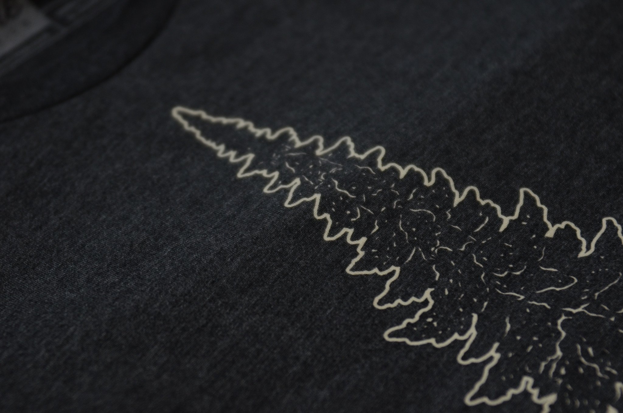 Mighty Pine Tee in dark gray featuring a white screen printed design of a pine tree, made from soft cotton and polyester blend.