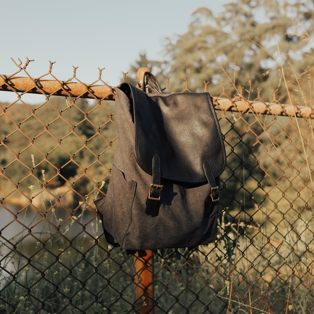 Shaun Canvas Cinched Backpack featuring vegan leather trims, padded straps, and water bottle holders, perfect for adventurers.