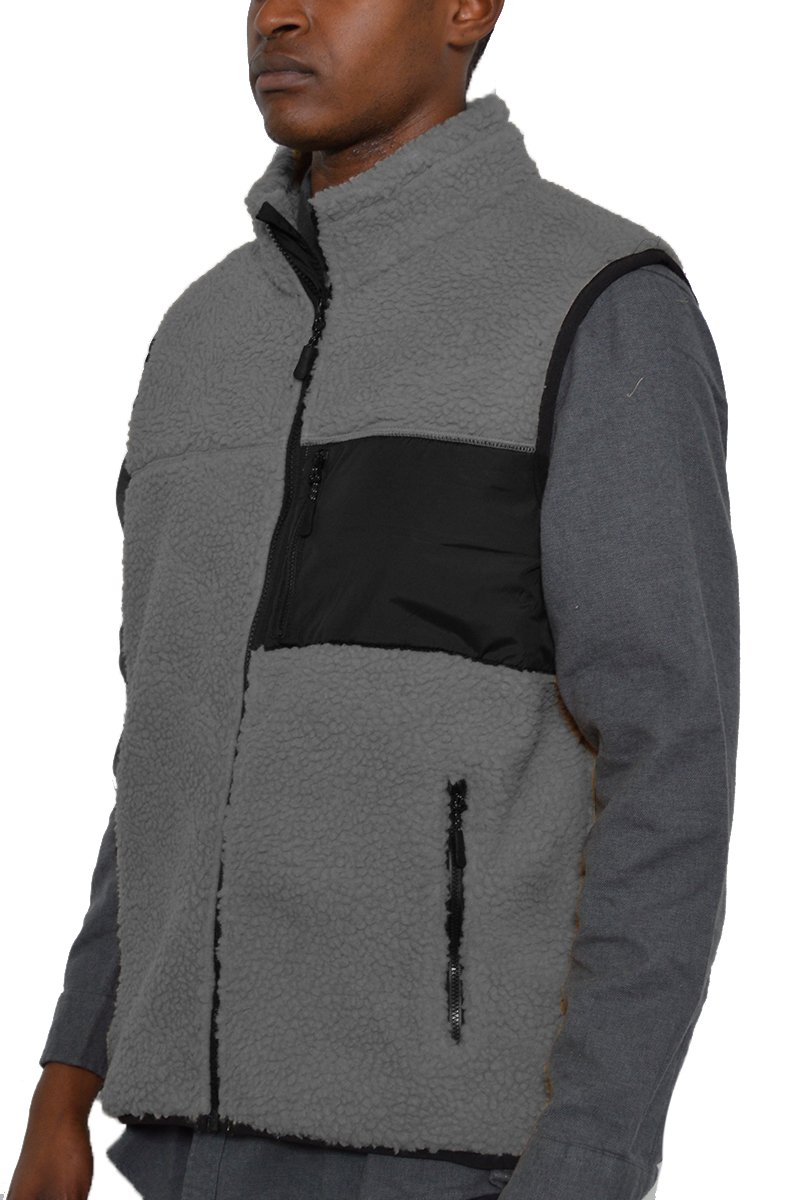 A cozy Sherpa fleece vest with a zip-up front, featuring a chest pocket and side zippered pockets, perfect for layering in cold weather.