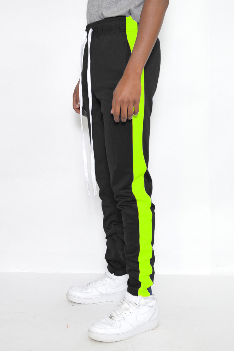 A pair of slim fit track pants featuring a single stripe detail, tug-free zipper closure, and hidden ankle zipper, displayed on a neutral background.