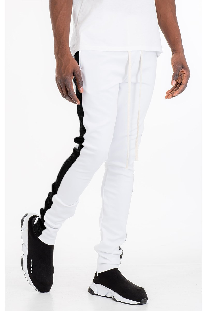 A pair of slim fit track pants featuring a single stripe detail, tug-free zipper closure, and hidden ankle zipper, made from polyester and spandex.