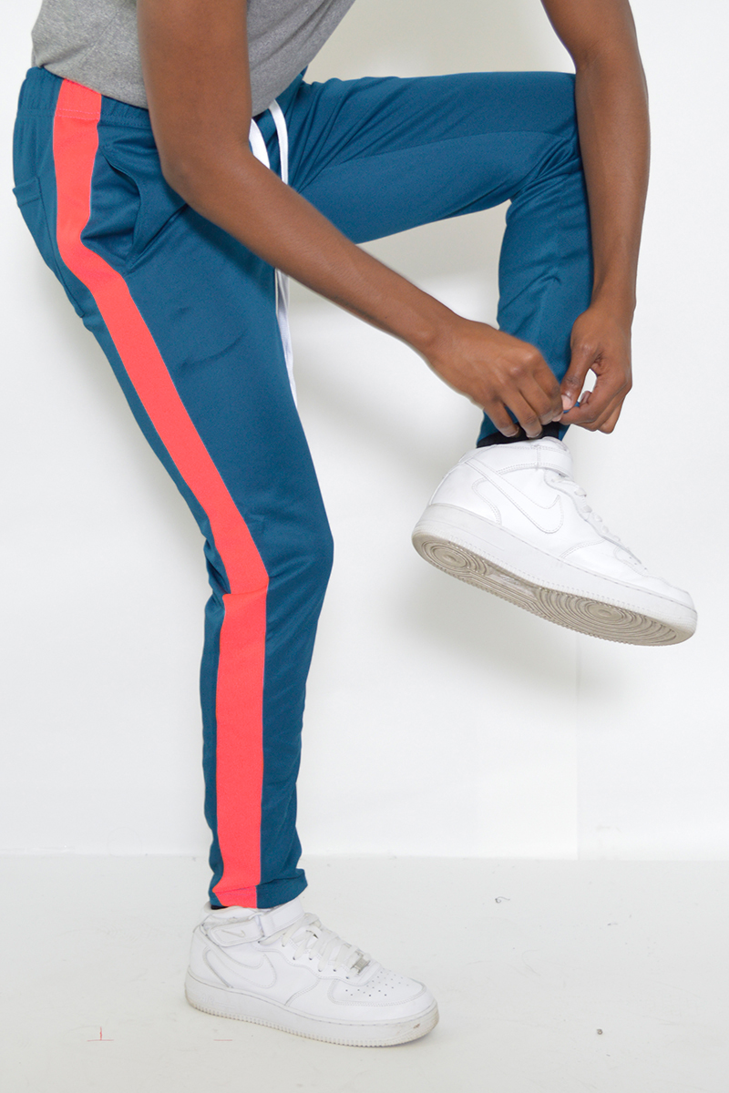 A pair of stylish slim fit track pants featuring a single stripe detail, tug-free zipper closure, and hidden ankle zippers, perfect for active wear.