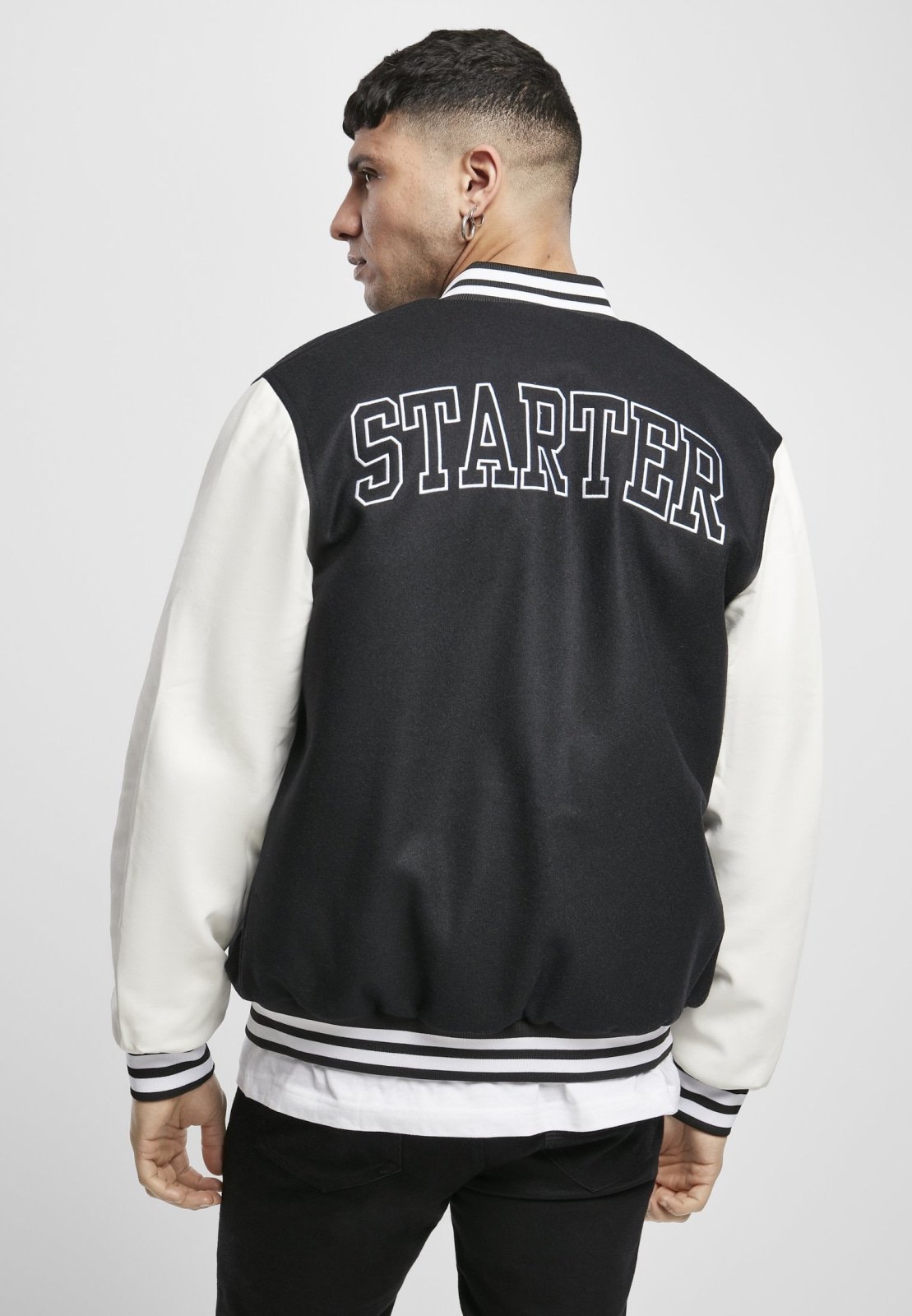 Standard College Jacket featuring a black body and white imitation leather sleeves, with double-striped cuffs and embroidered branding.