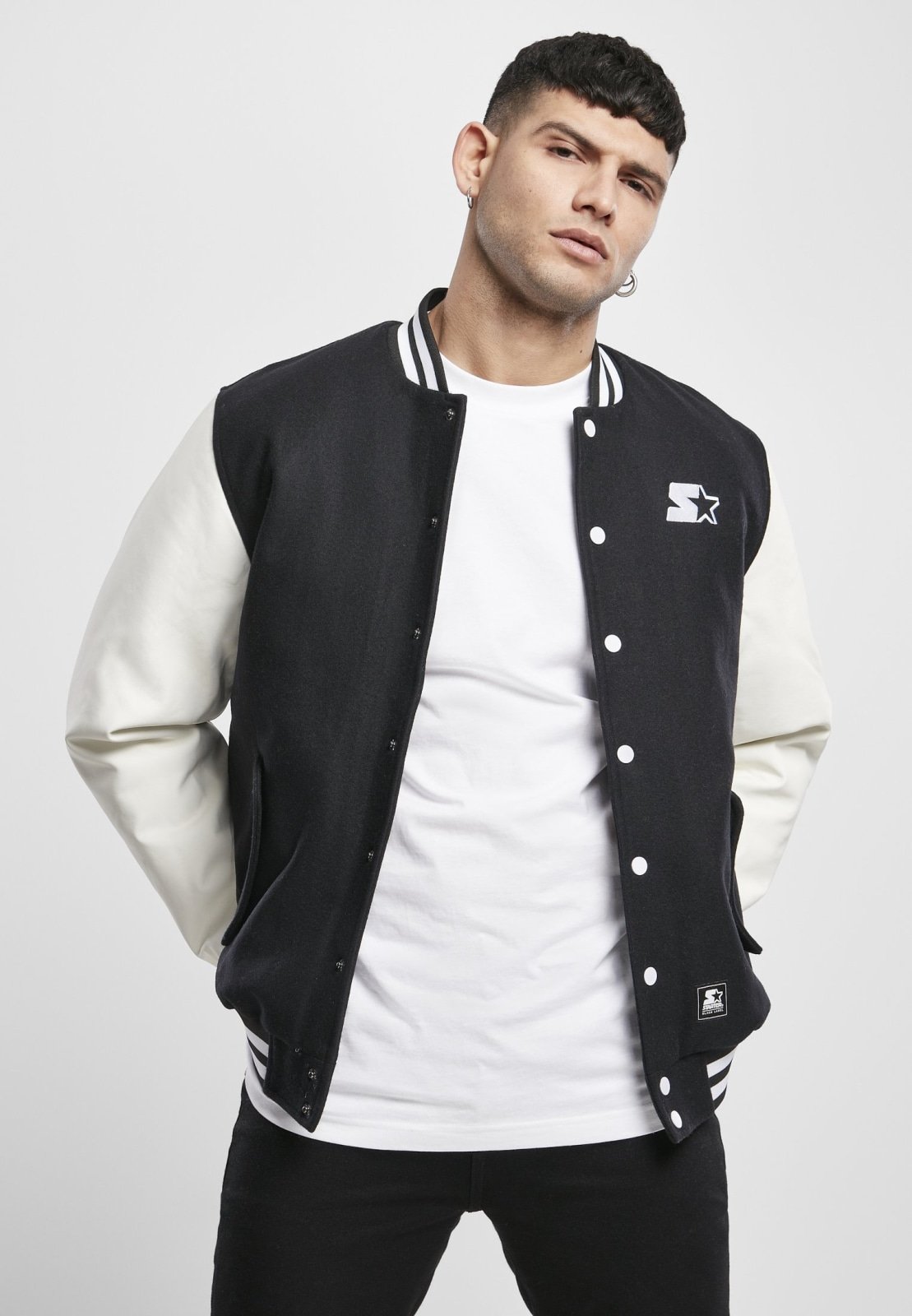 Standard College Jacket featuring a black body and white imitation leather sleeves, with double-striped cuffs and embroidered branding.