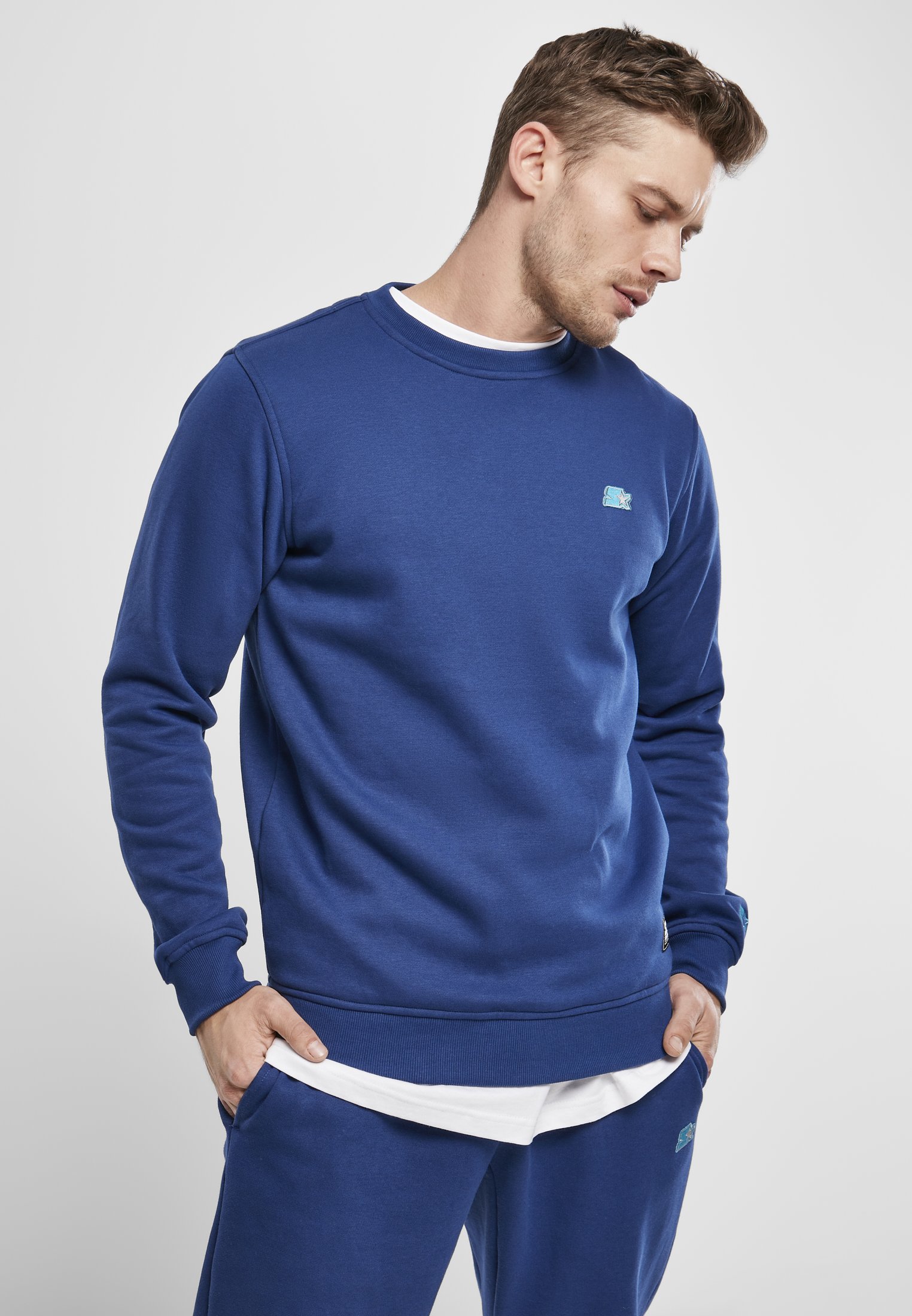 A cozy Starter Essential Crewneck Sweatshirt in various colors, showcasing its soft brushed fleece fabric and classic crewneck design.