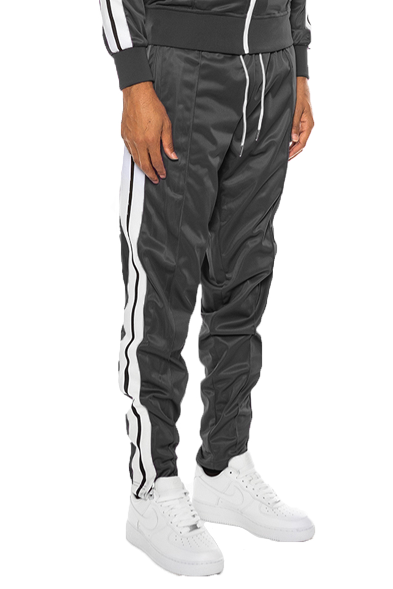 A pair of stylish striped tape track pants featuring an elastic waist, drawstring, ankle zippers, and pockets, displayed on a neutral background.