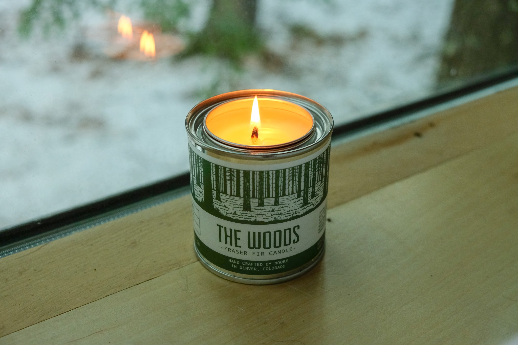 A beautifully handcrafted Woods Candle in a glass jar, showcasing its natural soy wax and elegant label inspired by the outdoors.